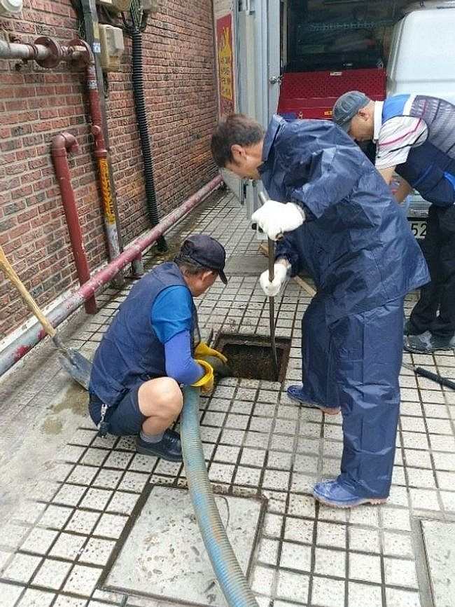맨홀 옆에서 준설 작업 중인 작업자들