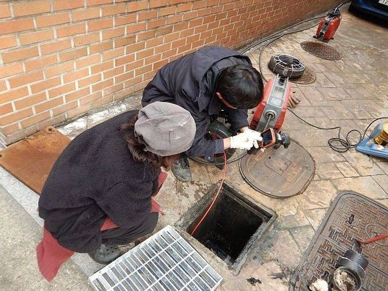 오수받이 앞에서 관로 세척 장비를 다루는 기사들